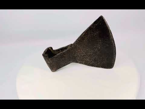 18th-century cast iron axe head from Europe or Colonial America, wedge-shaped with trapezoidal blade, triangular socket, faint punched motif, aged patina, and oxidation, reflecting historical tool craftsmanship.