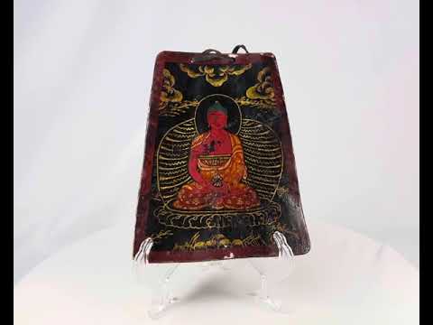 Late Qing Dynasty Tibetan devotional plaque, circa 19th century, hand-painted with vivid polychrome depiction of a seated Buddha in red and gold robes, surrounded by radiant aureole and cloud motifs; crafted on a rectangular wooden panel with suspension cord, showing surface wear and patina from ritual use.