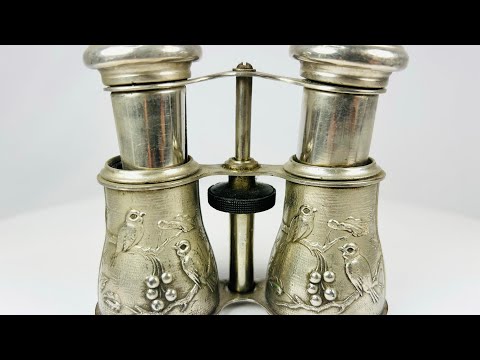 Antique 19th century opera glasses with silver-plated body, finely engraved bird and floral motifs, and adjustable mechanism. Elegant collectible binoculars used for theater and opera viewing, with rich patina and decorative craftsmanship.