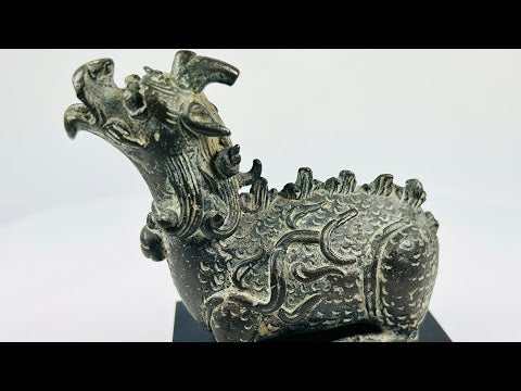 Chinese bronze censer in the form of a mythical Qilin with detailed scales, flame motifs, and open mouth for incense diffusion, mounted on a black display base.