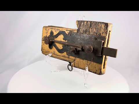 Rare 18th-century colonial wooden locking mechanism with original hand-forged iron hardware, including bolt, latch, and key ring; mounted on aged yellow-painted wood with visible wear, rusted fittings, and patina, illustrating early security technology and craftsmanship of the colonial era.