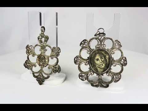 360° rotating view of a pair of Southern European silver devotional pendants with Christ and saint medallions.