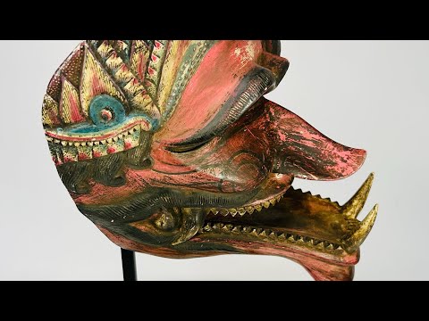 A late 19th-century Javanese carved wooden Cakil mask with sharp teeth, curved nose, crown-like decoration, and traces of red, gold, and black polychrome paint, used in Wayang Kulit performances to depict a demon antagonist.