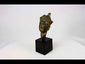 Antique Tibetan gilded bronze Buddha head with ornate crown, serene facial features, and traces of gilding, mounted on a black display base, photographed on a white background.