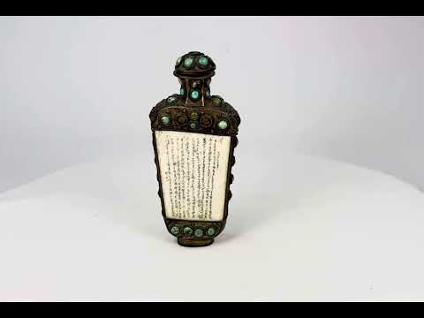 Ornate bronze ritual flask from the Sino-Tibetan border region, decorated with cabochon turquoise and green stones, carved bone panels with Tibetan or Sanskrit inscriptions, and guardian lion masks in relief, 5 inches tall by 2.5 inches wide, late Qing Dynasty, circa late 19th century.