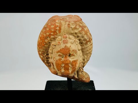 Pre-Columbian terracotta head fragment, circa 500–1200 CE, with serene facial features, ornate headdress, and traces of red and white pigment.