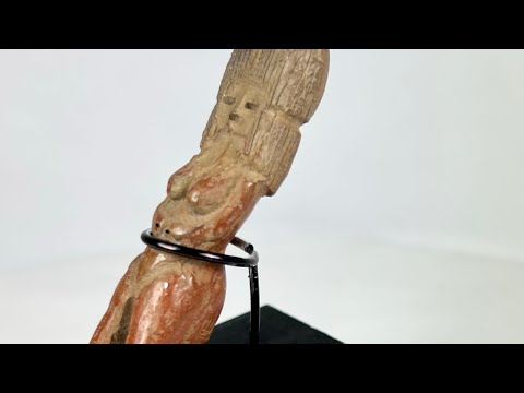 Molded terracotta figurine of seated female from Classic Veracruz culture, with vertical ridged headdress, bent legs, hands raised to face, incised facial features, and traces of red slip; mounted on black display stand; circa 600–900 CE, Gulf Coast of Mexico.