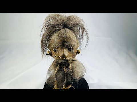 360-degree view of a modern replica Jivaroan shrunken head, showcasing detailed stitching, horse hair, and glass globe display