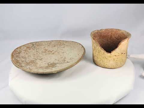 Set of Neolithic terracotta pottery, including a shallow bowl and cylindrical vessel fragment, circa 4000–2000 BCE, with natural earthy tones, unglazed surfaces, and aged patina.