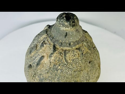 Video of a 10th–12th century Islamic ceramic hand grenade from Greater Persia, showcasing close-up details of its engraved surface, ancient patina, and rounded body.