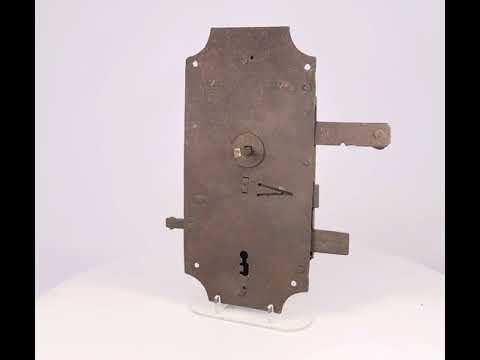 18th-century European hand-forged iron door lock with rectangular form, exposed keyhole, scroll springs, and aged patina.
