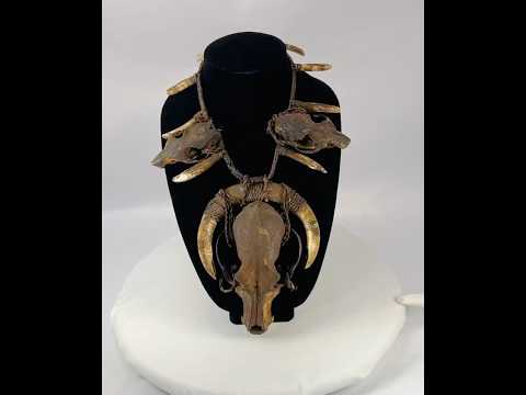 Ethnographic ceremonial necklace featuring a central wild dog skull, flanked by rodent skulls and pig teeth, strung on woven twine, used in shamanic or warrior rituals.