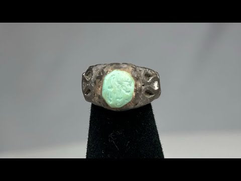 Ancient Neo-Assyrian silver ring from Mesopotamia (modern-day Iraq), 9th–7th century BCE, featuring a raised turquoise bezel and engraved winged serpent with mythical beast motifs. Silver band with natural patina showcases Assyrian craftsmanship, symbolizing divine protection, authority, and spiritual power.