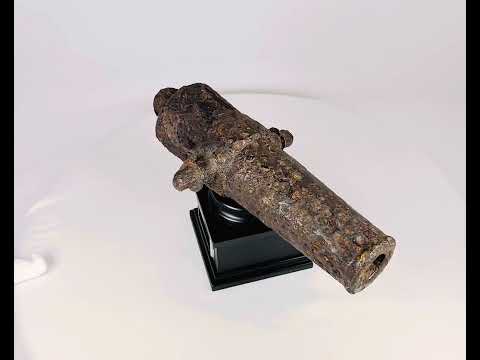 Rusted miniature iron cannon from the British Civil War period, mounted on a black display stand, featuring original trunnions and hollow barrel, 17th century.