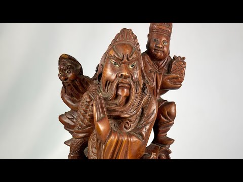 Antique Chinese Qing Dynasty-era wood carving of a warrior immortal figure, intricately detailed with flowing robes, fierce expression, and symbolic weaponry, standing atop a carved base; traditional hand-carved craftsmanship with dark polished patina, reflecting religious and cultural artistry of Qing Dynasty China.
