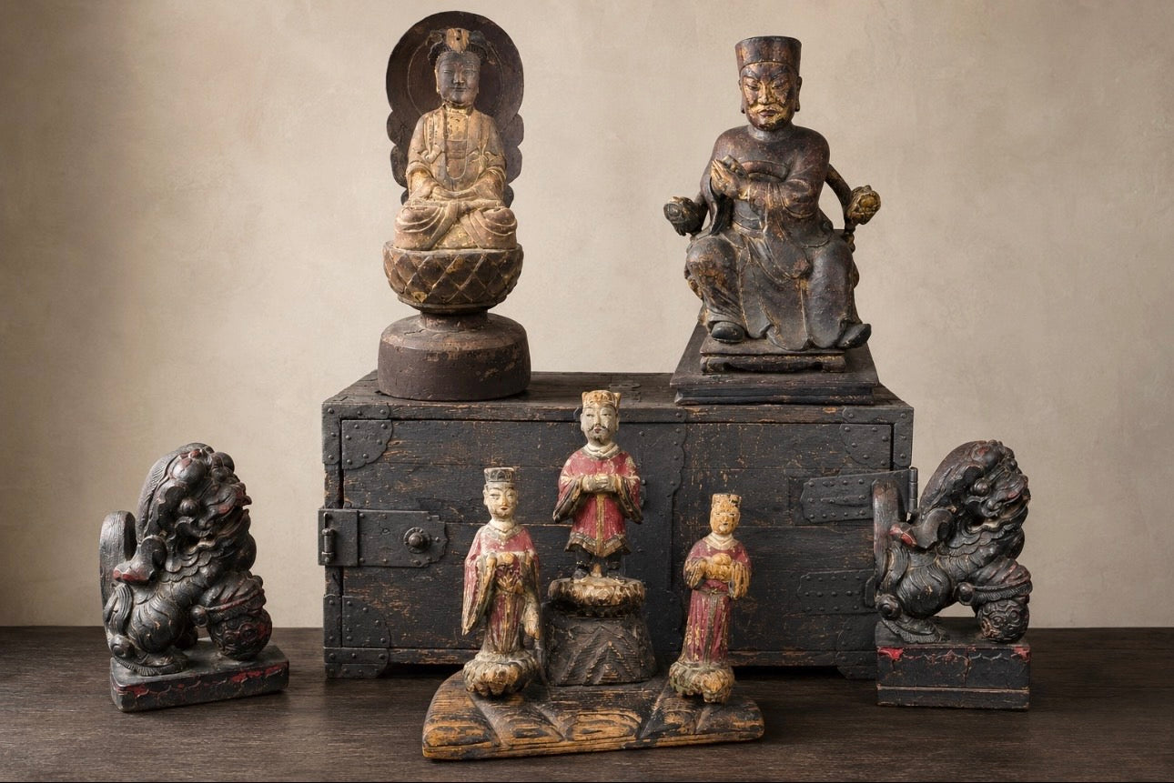 Curated display of antique Chinese carved figures and guardian lions with a Japanese Edo-period iron-bound ship chest.