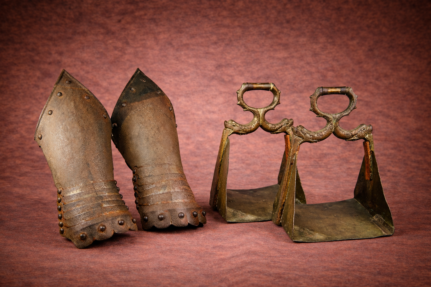 Medieval armor leg guards and antique bronze horse stirrups displayed by Relic & Rarity