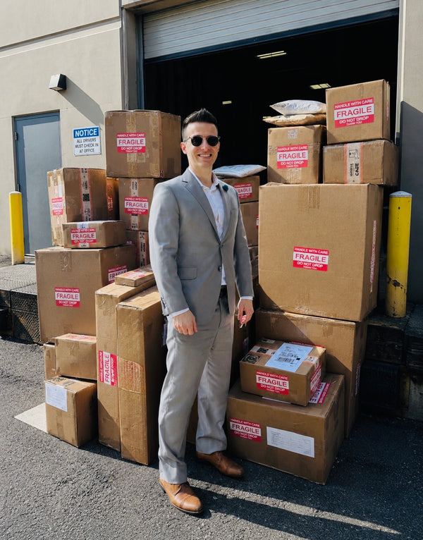 Jordan Thomas of Relic & Rarity standing in front of carefully packed artifact shipments outside the company's warehouse, showcasing professional worldwide shipping and protective packaging for historical artifacts and antiques